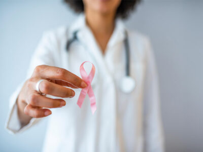 medico donna con in mano fiocco rosa simbolo della lotta contro i tumori al seno. Fondazione della Comunità Bresciana