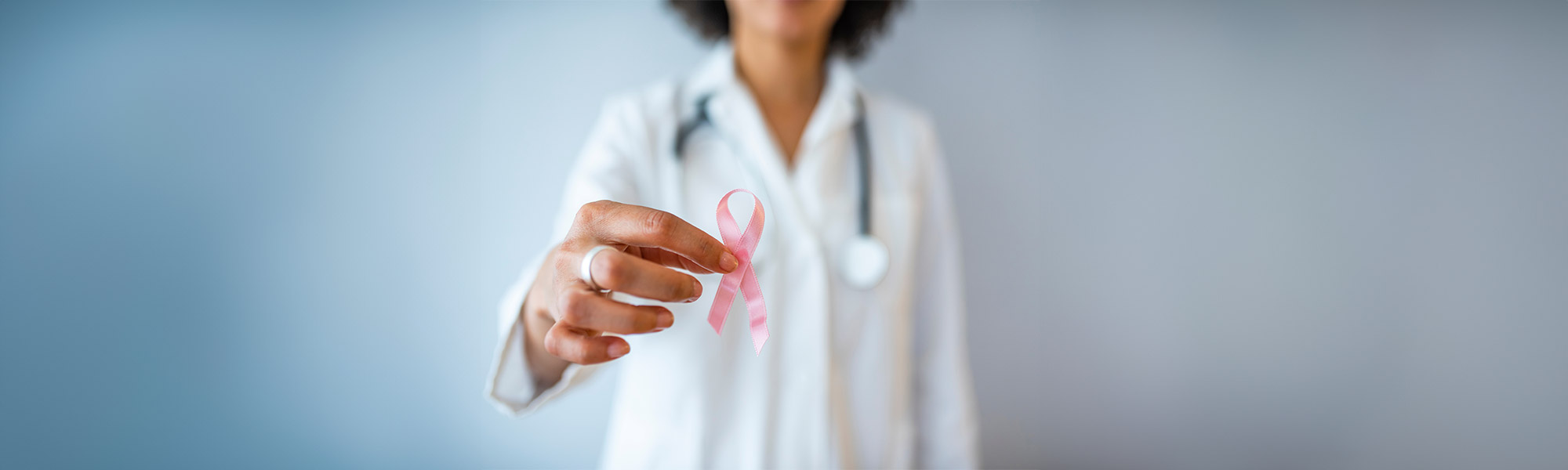medico donna con in mano fiocco rosa simbolo della lotta contro i tumori al seno. Fondazione della Comunità Bresciana